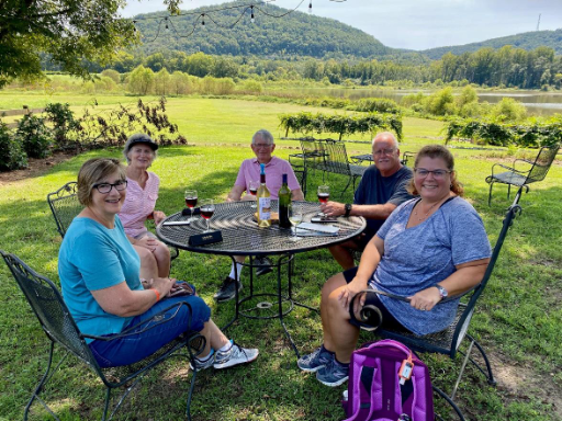 Group gathered at a table with winery landscape in the background.